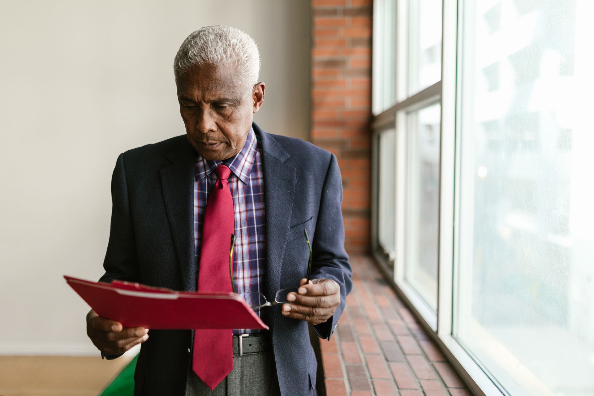 A senior Black executive in a suit reviewing documents in an office