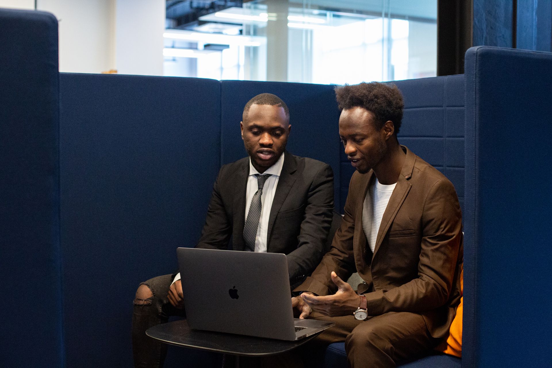 Two Black business professionals reviewing figures on a laptop in a modern office